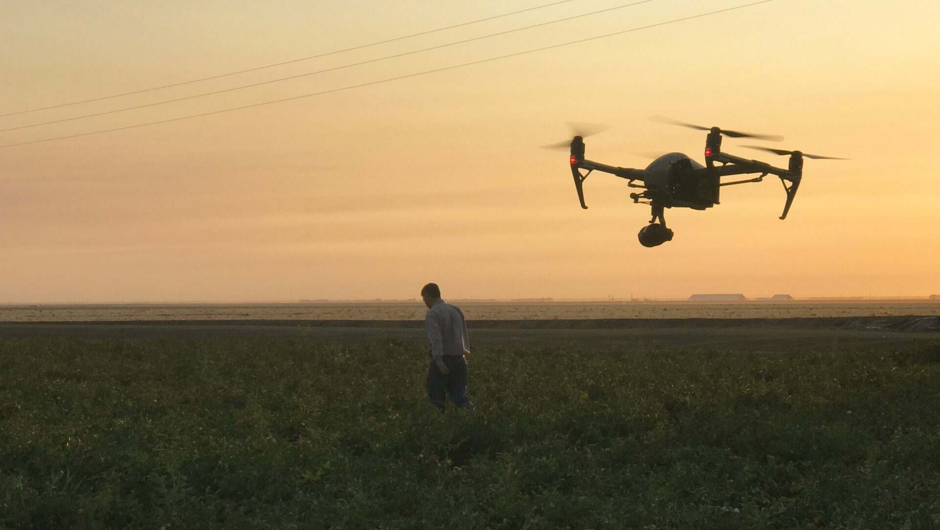 Camera drone following subject in a field at sunset